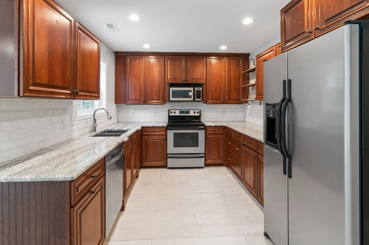 Spacious kitchen featuring stainless steel appliances, wooden cabinets, and granite countertops.