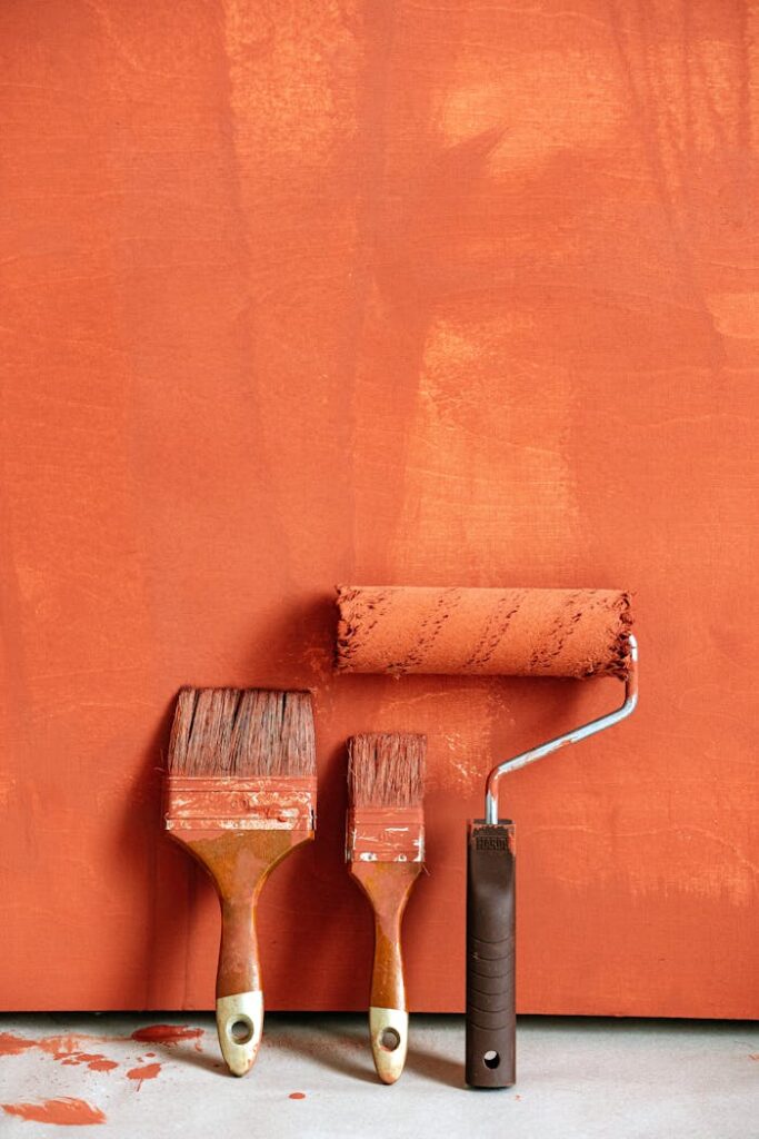 pexels-photo-5799086 Close-up of paintbrushes and roller with orange backdrop, perfect for home renovation concepts.